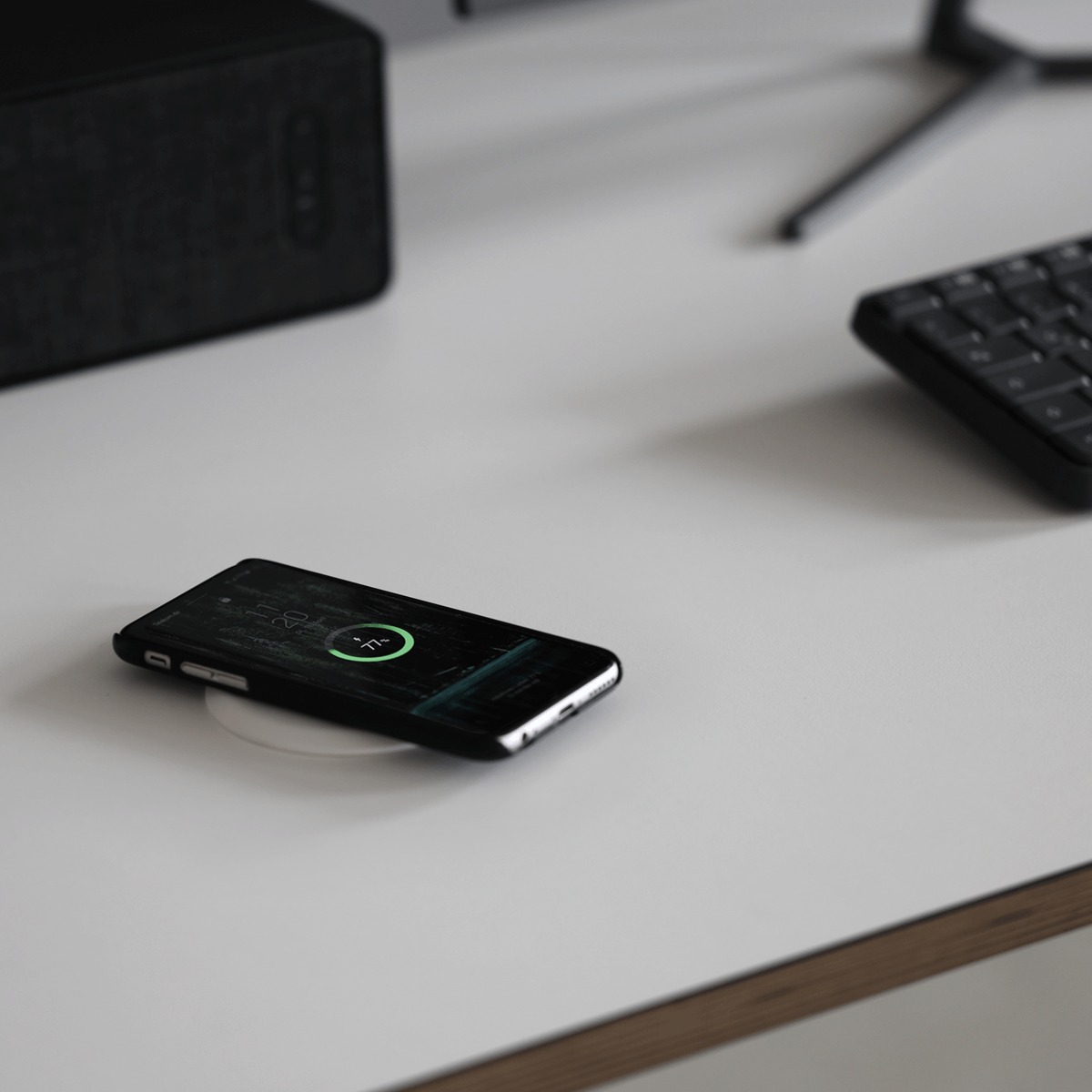 weißer wireless charger auf einem weißen Eliot Tisch mit einem Handy das geladen wird