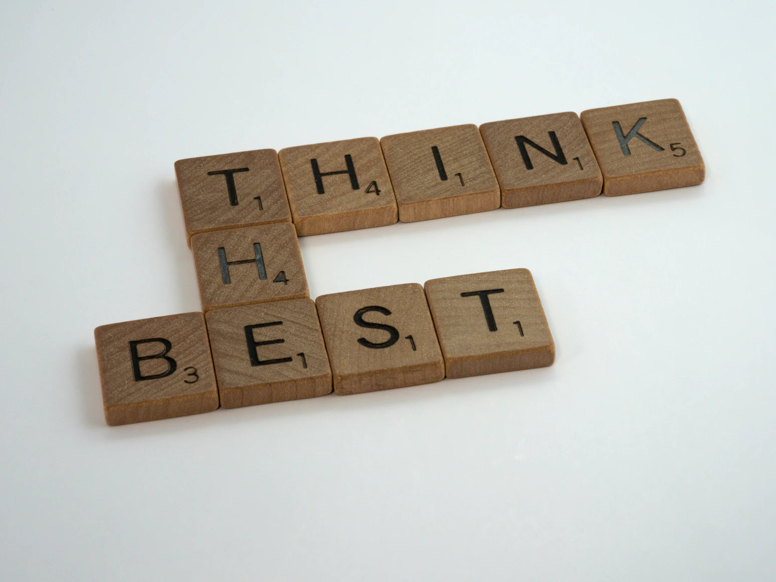 Scrabble-Bausteine aus Holz bilden die Worte "Think the best"