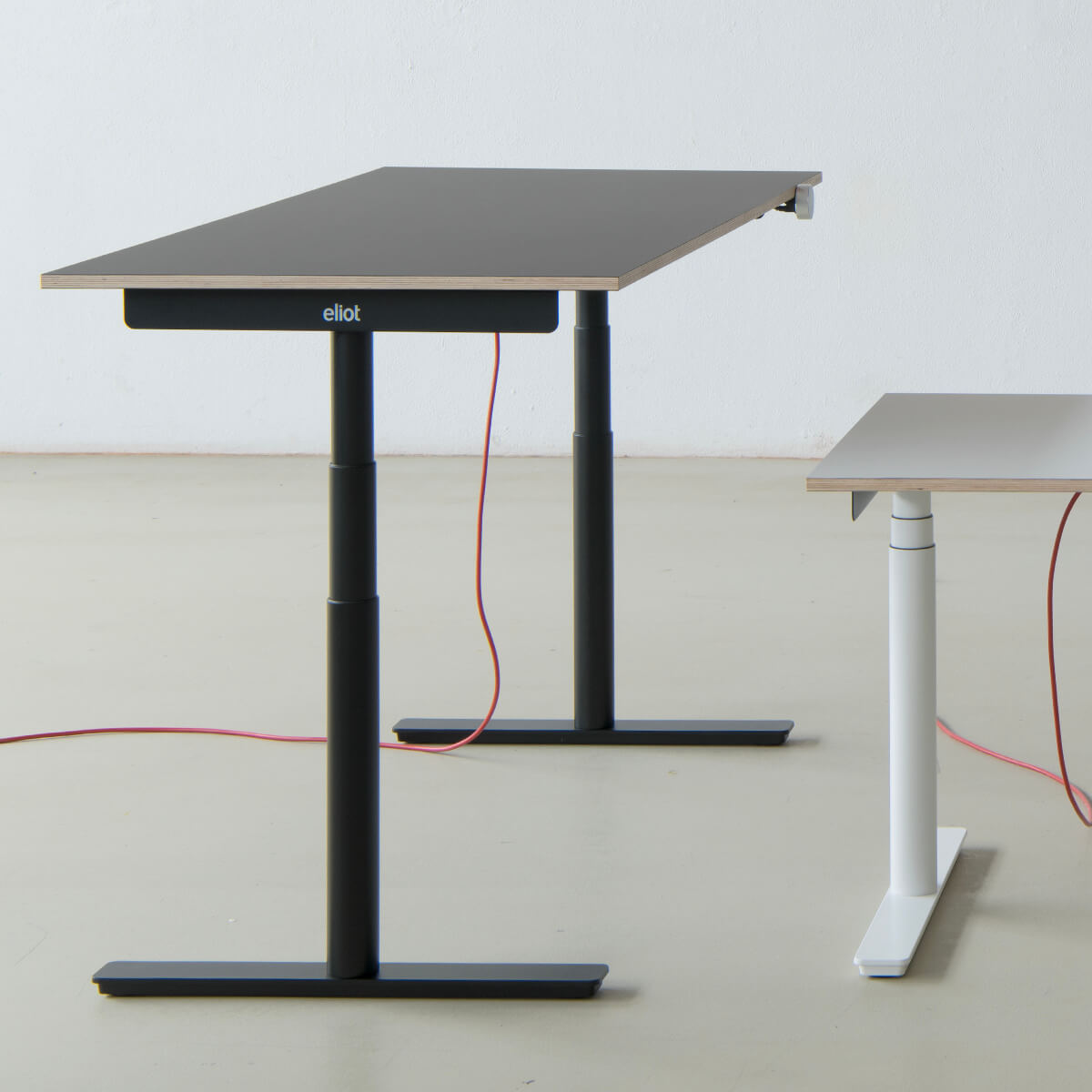 Profil eines schwarzen Eliot-Tisches mit grauer Tischplatte in einem leeren Raum neben einem kleinen Eliot in weiß