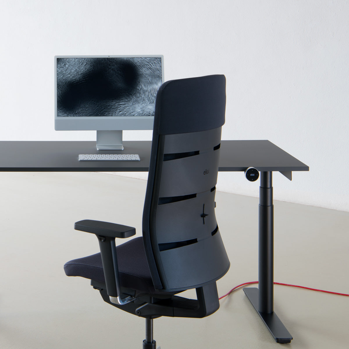 freigestellter ergonomischer Bürostuhl Spyn Plus Anthrazitgrau vor schwarzem Eliot Tisch