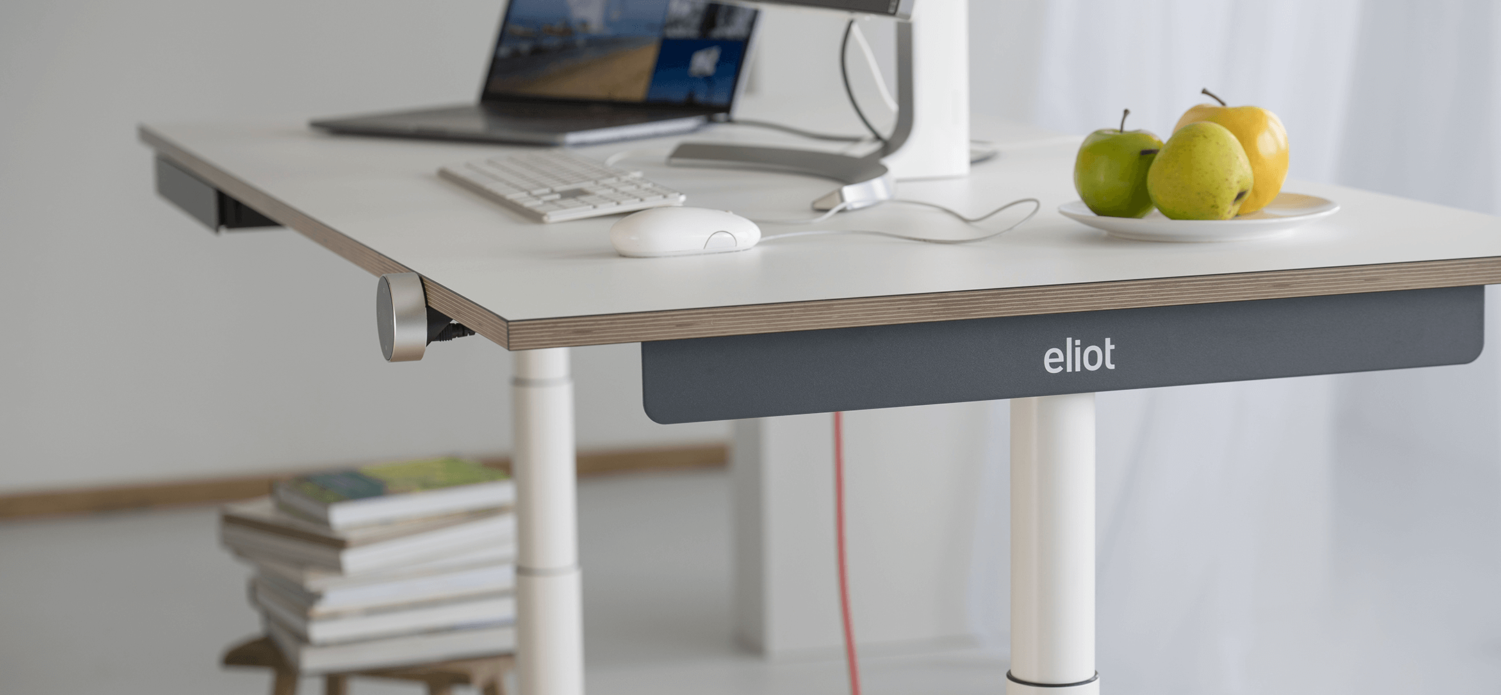 Höhenverstellbarer Schreibtisch Eliot Tiny im Halbprofil, darauf Obst und Computer
