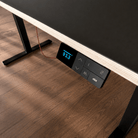 Nahaufnahme eines schwarzen und hölzernen Sitz-Steh-Schreibtisches der Smartfurniture GmbH mit dem elektronischen Bedienfeld Procontroller mit Memory-Funktion und LED-Höhenanzeige (93,3) auf einem Holzfußboden.