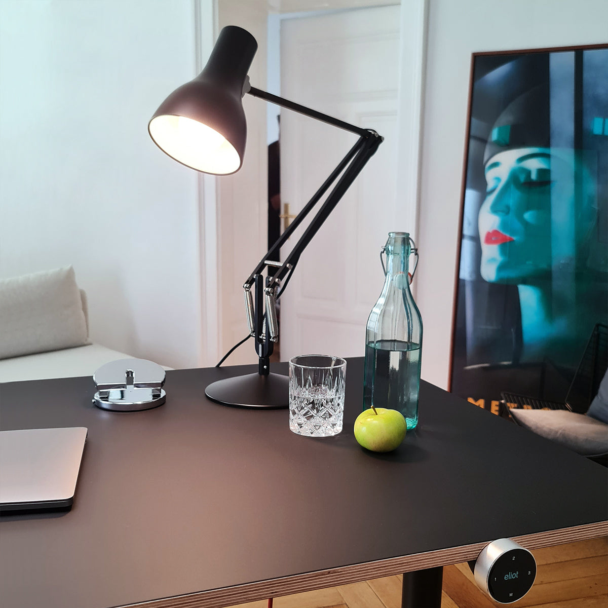 Anglepoise Schreibtischleuchte auf Eliot Schreibtisch, daneben Wasser und ein Apfel